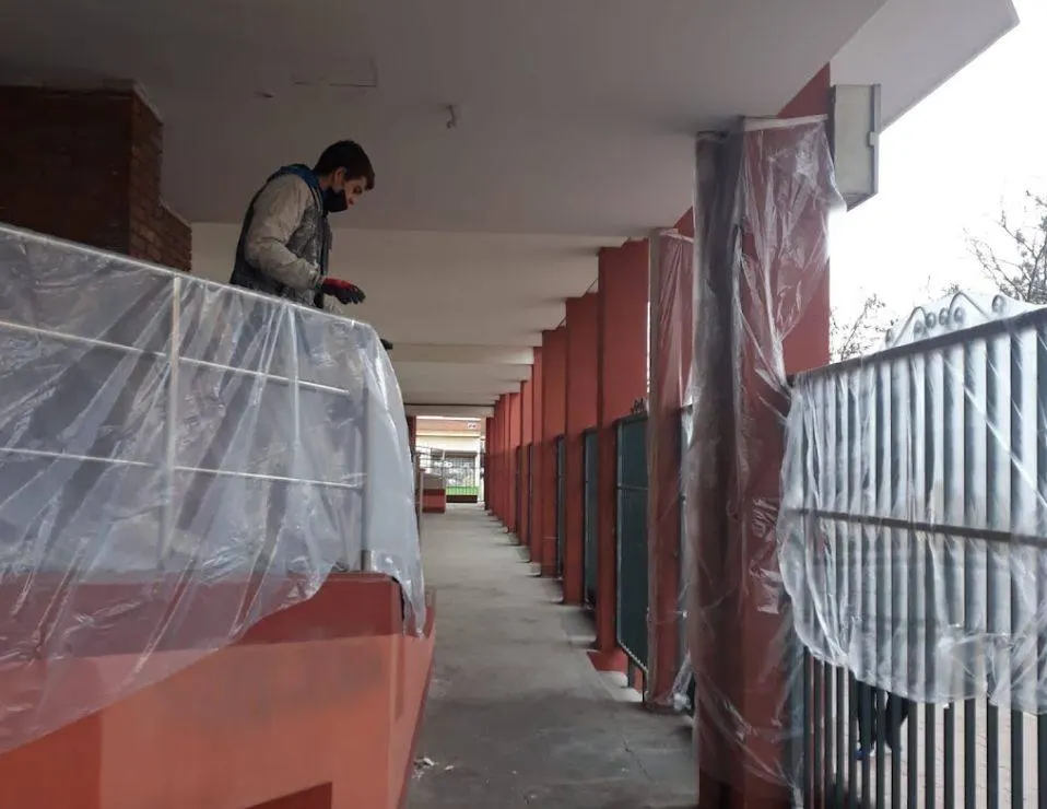 Pintor en un porche con barandillas y columnas protegidas con plásticos antes de pintar